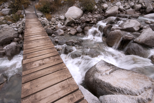 A wooden footbridge across glacial run-off in the Graian Alps.