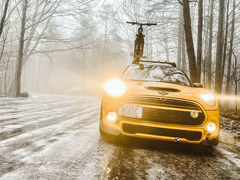 Toronto, Ontario, Canada- December 11, 2021. 2017 MINI COOPER S with fat bicycle on the roof,  in the winter forest  . This is the third generation model F56 , since BMW took over iconic brand of MINI. MINI featured in the photo is Cooper model with 4 doors. This compact car features engine build and designed by BMW, and packs even more power and torque than previous models, since 2002 to present. Original design clues and themes are still present on this brand new model. Mini has been around since 1959 and has been owned and issued by various car manufacturers.