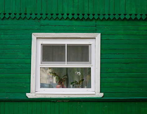 A bright green wooden wall with a small white-framed window