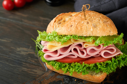 Sandwich. Tasty sandwich with ham or bacon, cheese, tomatoes, lettuce and grain bread on dark backgrounds. Delicious club sandwich or school lunch, breakfast or snack.