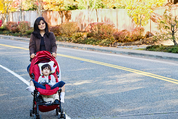 istock Mother walking with her disabled son in stroller 153698475