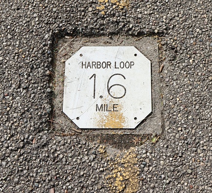 A close view on the silver metal distance sign on the path.