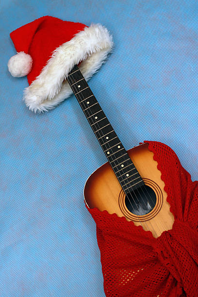 istock Christmas Guitar Wrapped In Shawl With Santa Hat On It 153698940
