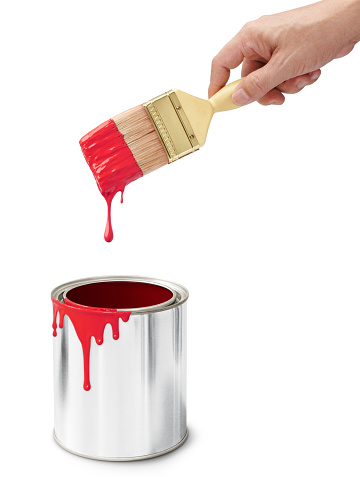 hand holding paintbrush after dipping into its bucket