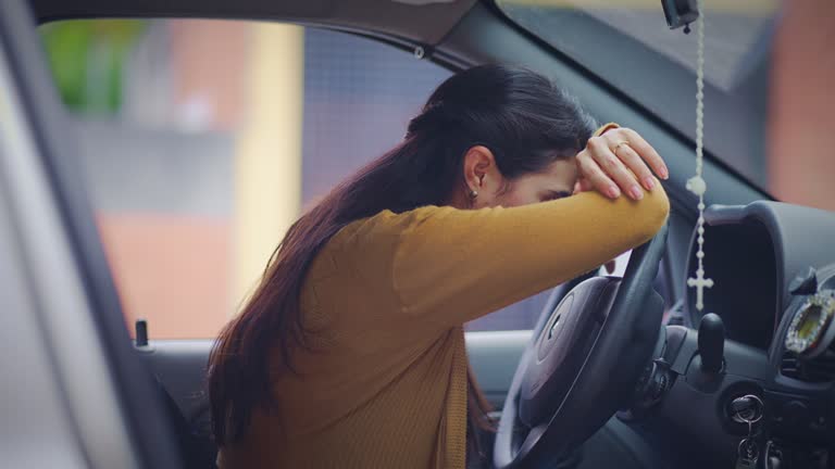 Sad Hispanic young woman feeling worried and stressed while sitting in driver's seat inside her car