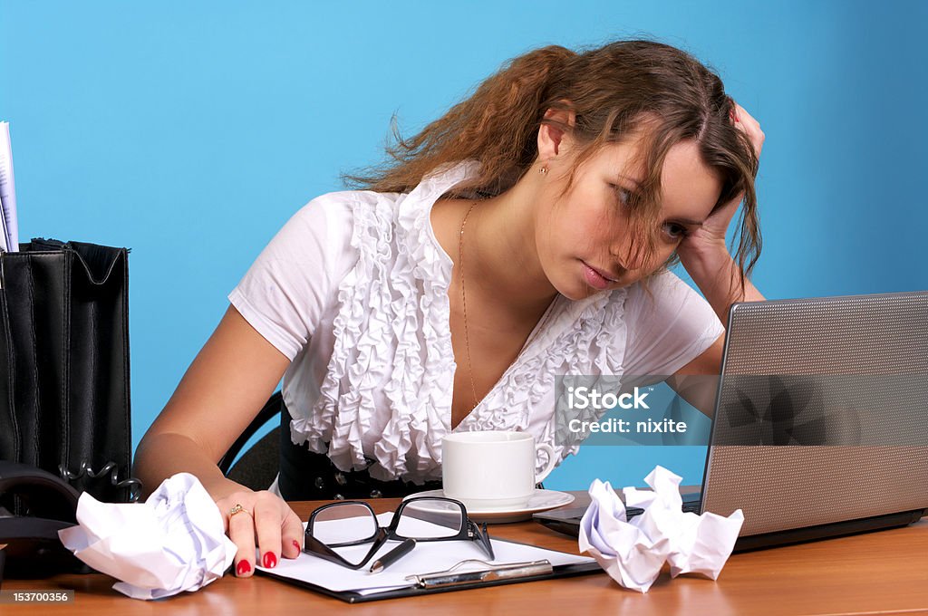 Tired business woman looking at laptop Beautiful young employer looking at laptop with troubled expression Adult Stock Photo