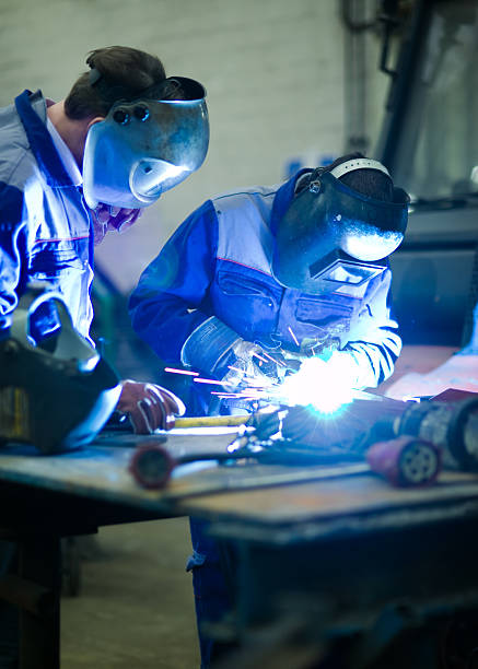 Welder education training Welder master with trainee at work welding mask stock pictures, royalty-free photos & images