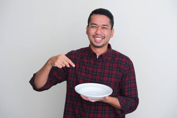 istock Adult Asian man smiling happy while pointing to empty dinner plate that he hold 1537025085