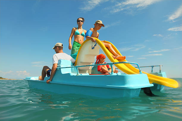 Family with boy and girl on pedal boat in sea stock photo