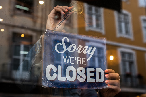 Woman holding We Are Closed sign