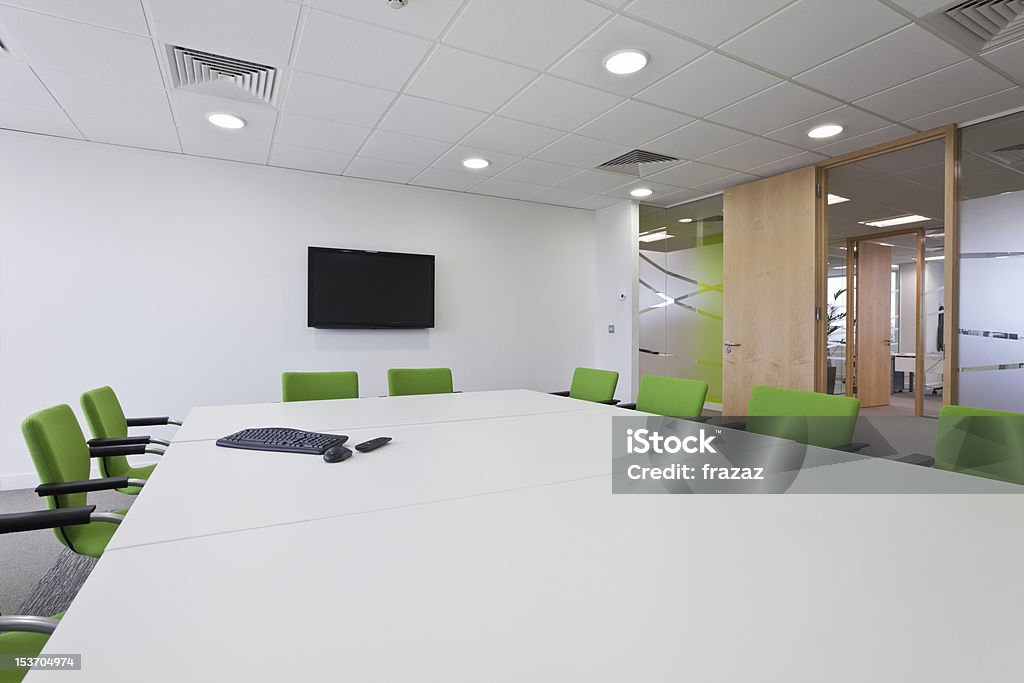 Modern furnished boardroom Fashionable modern boardroom with wall mounted television, bold colored chairs and white decor Architectural Feature Stock Photo