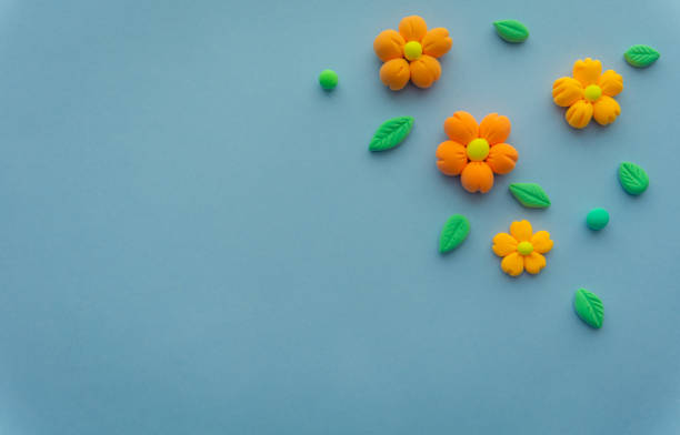 istock Airy orange flowers with green leaves made of light plasticine, a background with space for your text. Eco theme, plants and gardening 1537055452