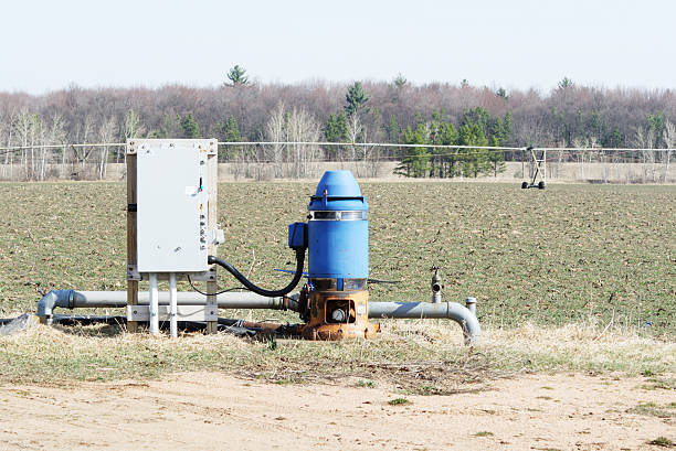 Blue Irrigation Well Well and electrical panel with pivot irrigation system in the background. wells stock pictures, royalty-free photos & images