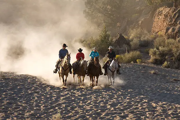 Wranglers taking a few moments in the early morning to have a conversation amongst themselves leaving a trail of dust behind them.