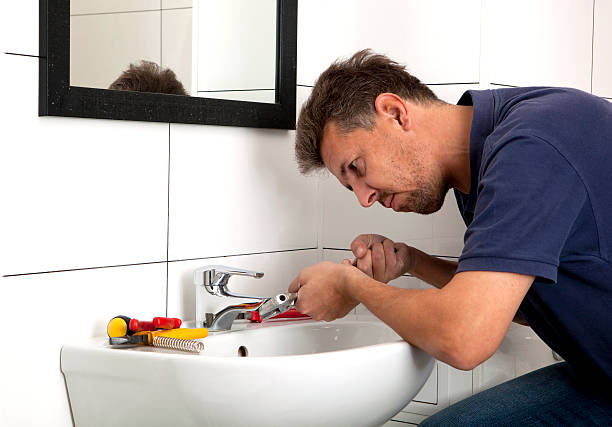 Male plumber fixing a sink with various tools stock photo