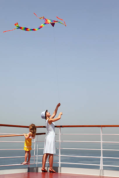 Woman with kite standing on deck, her daughter looking stock photo