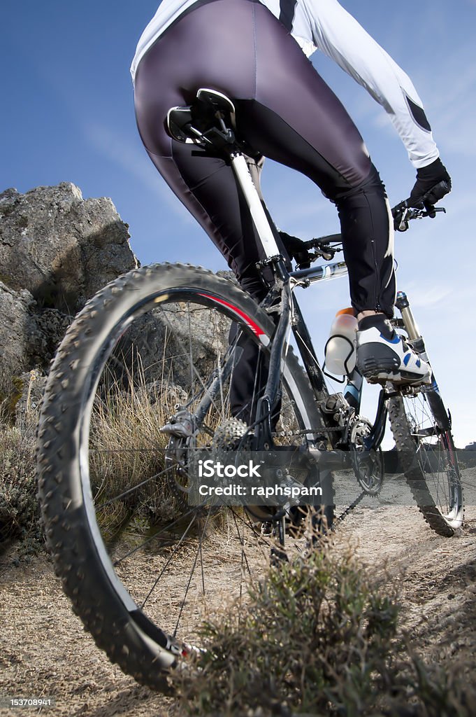 mountain bike Man riding a mountainbike on a mountain track, close-up view from behind Active Lifestyle Stock Photo