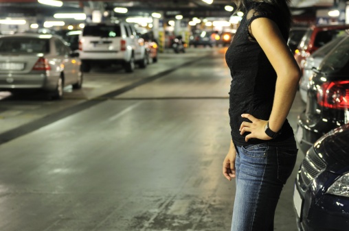 Young woman standing at car in underground parking place