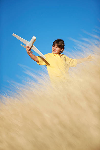 istock Young Boy Playing with Toy Glider Airplane in Grassy Field 153710500