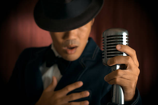 A male crooner singing tunes through a vintage microphone stock photo