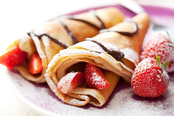 close up of two french style crepes, shallow dof. Some ingredients in the background