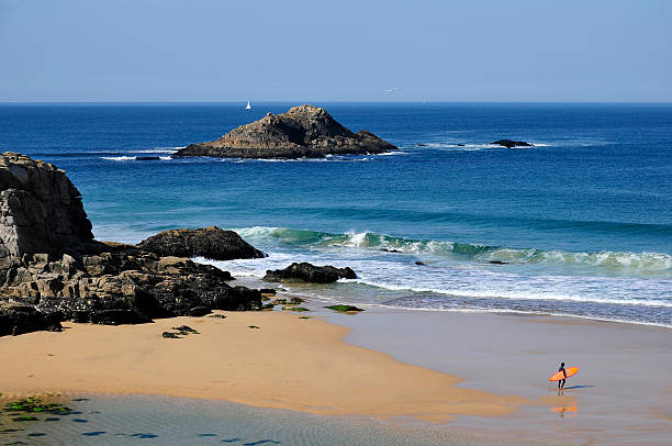 Beach with one surfer of Port Bara on the rocky wild coast of the peninsula of Quiberon in the Morbihan department in Brittany in north-western France.