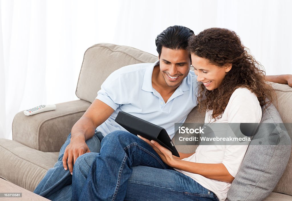 Lovely couple watching videos together sitting on their sofa Lovely couple watching videos together sitting on their sofa at home Adult Stock Photo