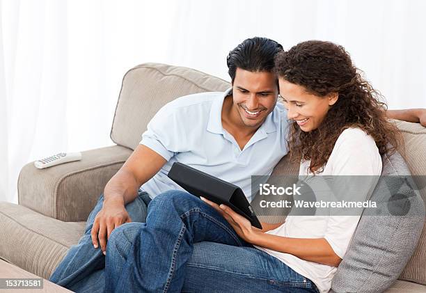 Lovely Couple Watching Videos Together Sitting On Their Sofa Stock Photo - Download Image Now