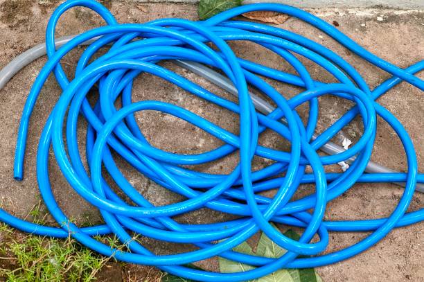 istock spiral blue hoses laying on the ground next to a green leaf. 1537142261