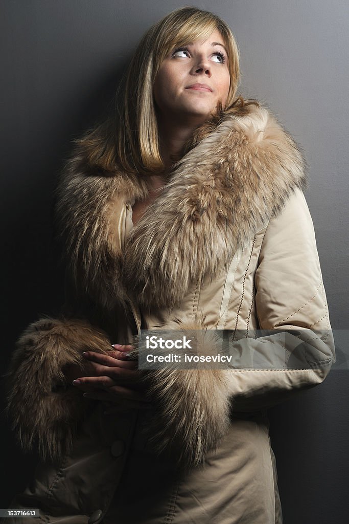Fashionable blonde girl in fur coat Blonde girl in cream coat with fur applications Long Coat Stock Photo