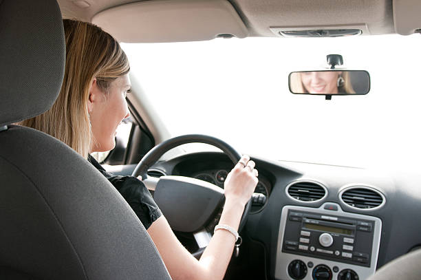 istock Woman driver who can be seen in rearview mirror smiling 153718070