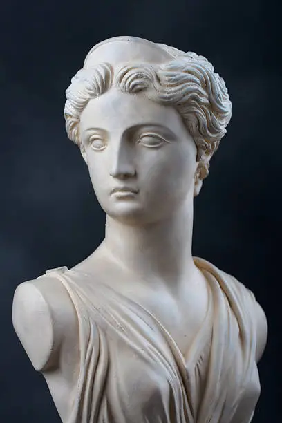 A copy of a stone bust of the Greek Goddess Artemis, daughter of Zeus, twin sister of Apollo.  This photograph provides a 2/3 view of the face and has dramatic low key lighting.