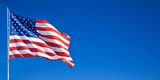 American flag waving in blue sky stock photo