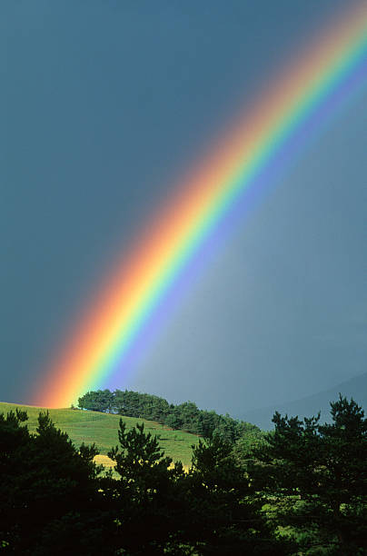 Rainbow coming up over a hillside stock photo
