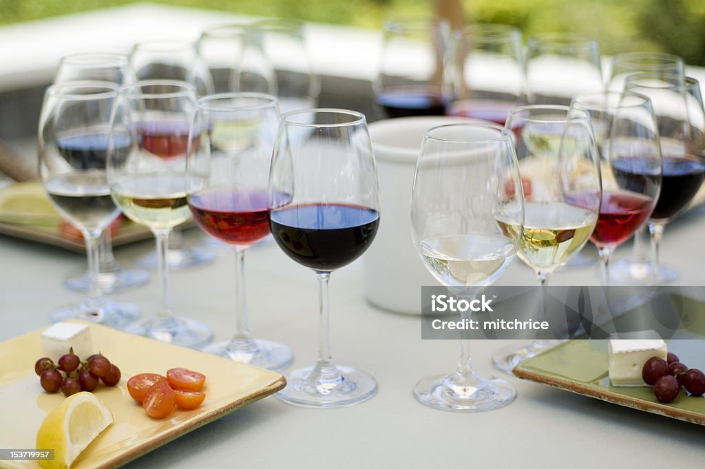 Food and Wine Pairing A selection of foods and wines arranged for a tasting. Four place settings, each with four wine glasses and a plate of four food types. Cheese Stock Photo