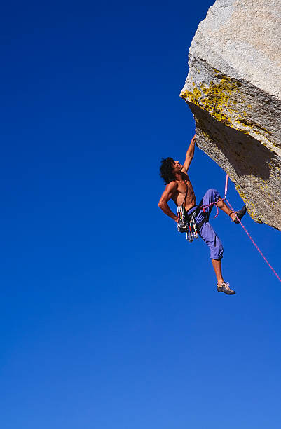 Climber clinging to a cliff. stock photo