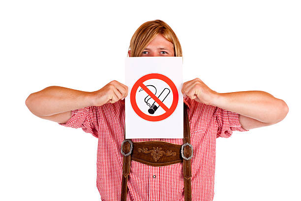 Bavarian man holds no-smoking-rule sign in front of face stock photo