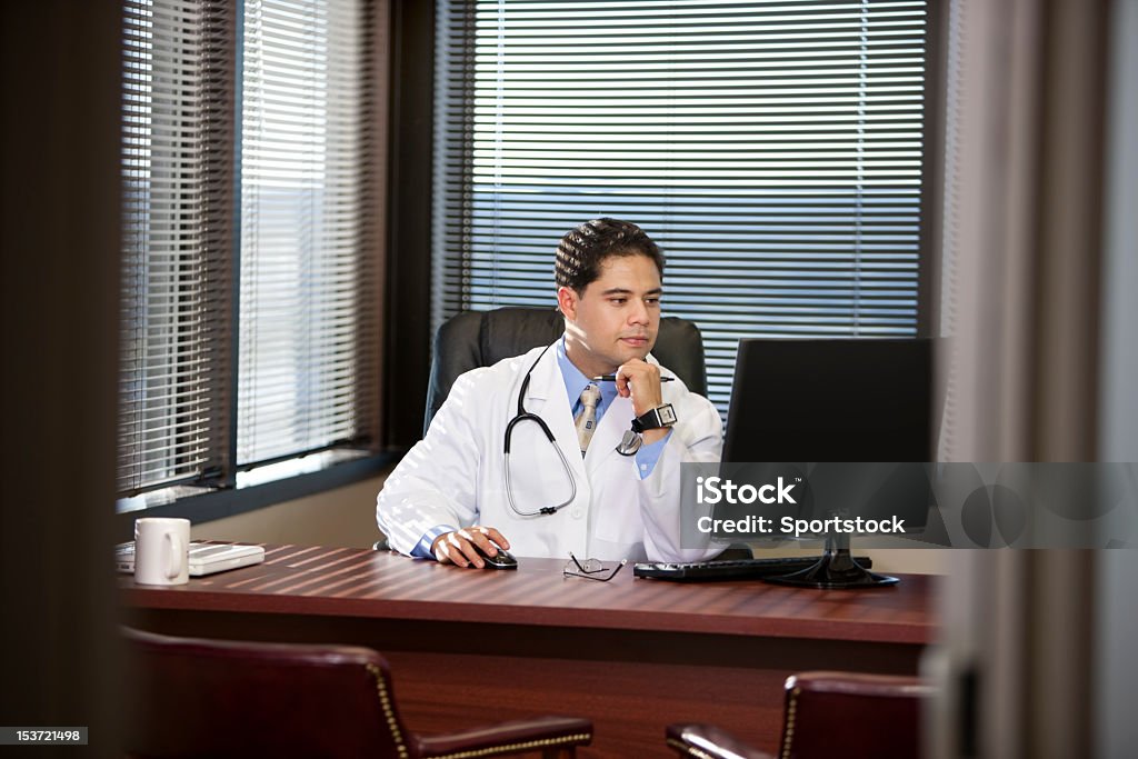 Hispanic Mann im Laborkittel Blick auf Computer - Lizenzfrei Krankenpfleger Stock-Foto