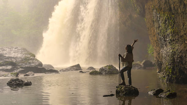 asian female tourists, trekking, experience the atmosphere of haew suwat waterfall in tropical forest. khao yai national park, thailand. young asian woman trekking to see waterfall in middle of forest - erawan falls fotos imagens e fotografias de stock