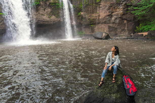 asian female tourists, trekking, experience the atmosphere of haew suwat waterfall in tropical forest. khao yai national park, thailand. young asian woman trekking to see waterfall in middle of forest - erawan falls fotos imagens e fotografias de stock