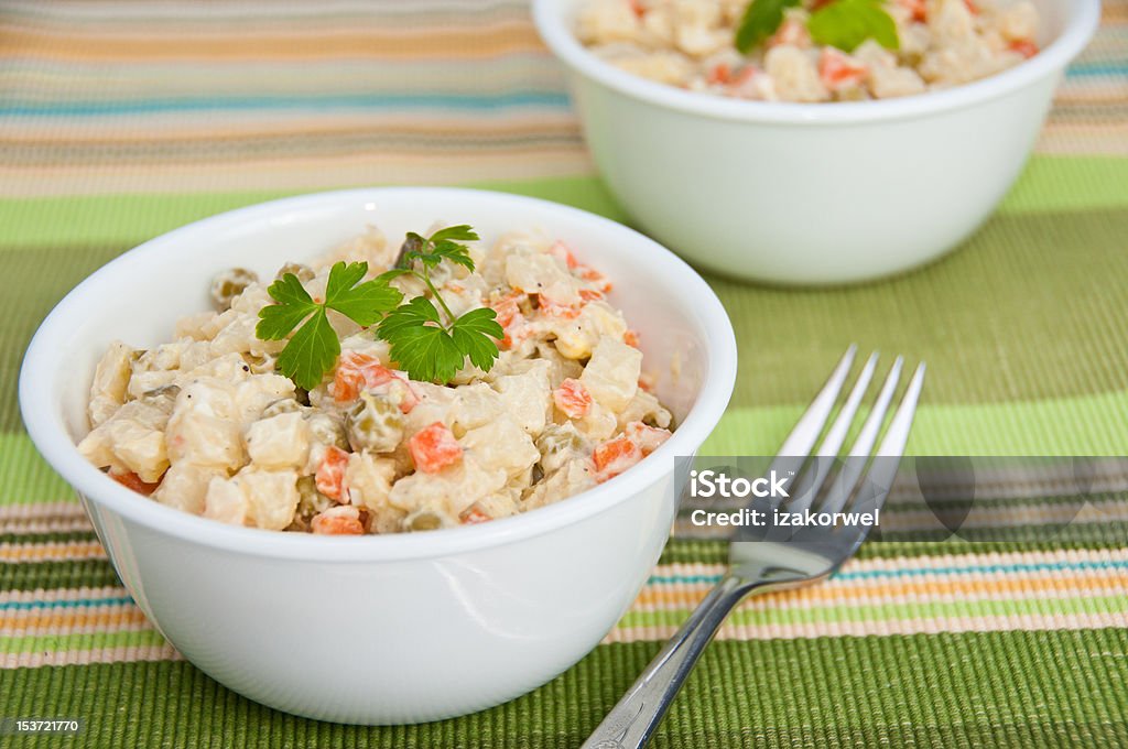 Two bowls of potato salad on green napkin Two bowls of potato salad with carrots and sweet peas and a fork on a green decorative napkin Bowl Stock Photo