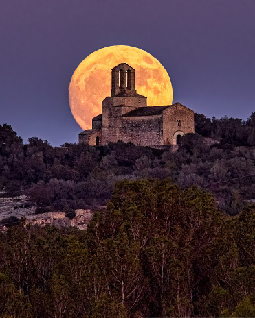Full moon raising behind the church in Olerdola, Catalonia, Spain