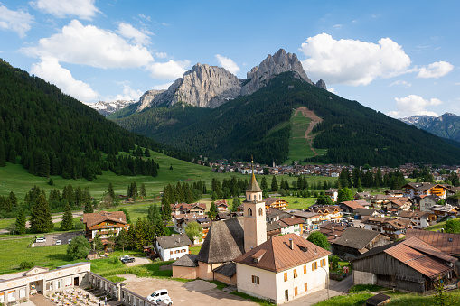 Beautiful alpine village with catholic church on the foreground. Val di Fassa, Italy