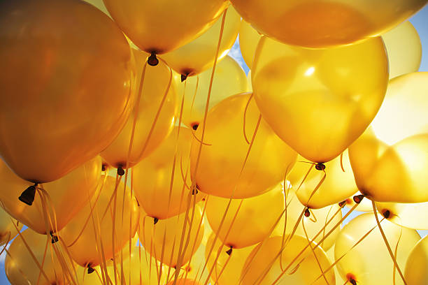 jaune vif ballons rétro-éclairé avec ciel arrière-plan - yellow balloon photos et images de collection