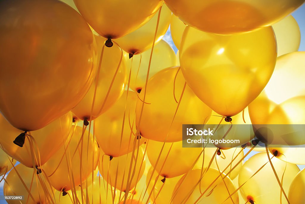 Bright yellow balloons backlit in sky background Background of bright yellow inflatable balloons up in the air, backlit by sun. Yellow Stock Photo