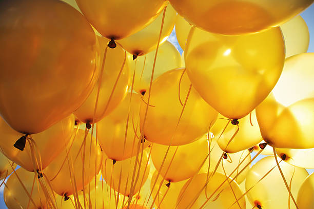 amarelo brilhante balões no céu com iluminação de fundo - yellow balloon - fotografias e filmes do acervo