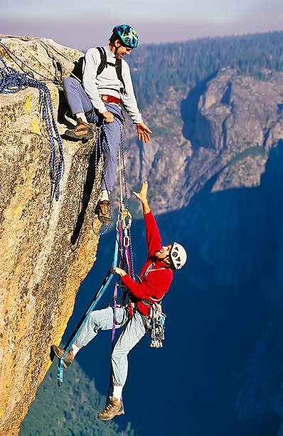 Team of climbers reaching the summit of a rock pinnacle.
