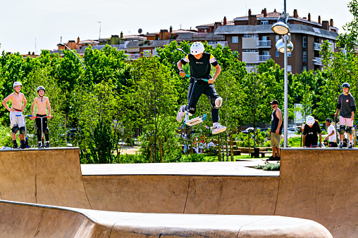 Igualada, Barcelona; June 25, 2023: Young man practicing Scootering (Freestyle Scootering) in the new SkatePark of the central park of Igualada, Barcelona, Spain
