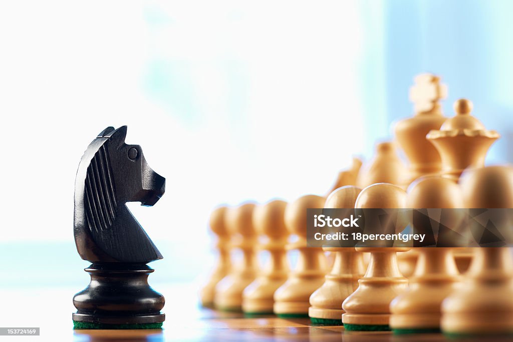 Chess black knight challenges white pawns Chess black knight challenges white pawns abstract background Black Color Stock Photo
