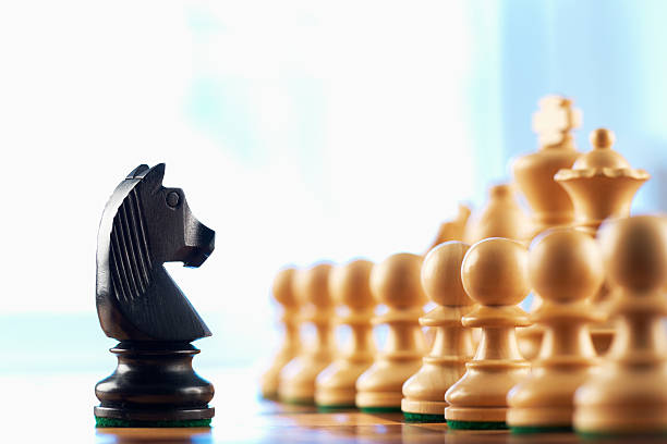 Chess black knight challenges white pawns stock photo